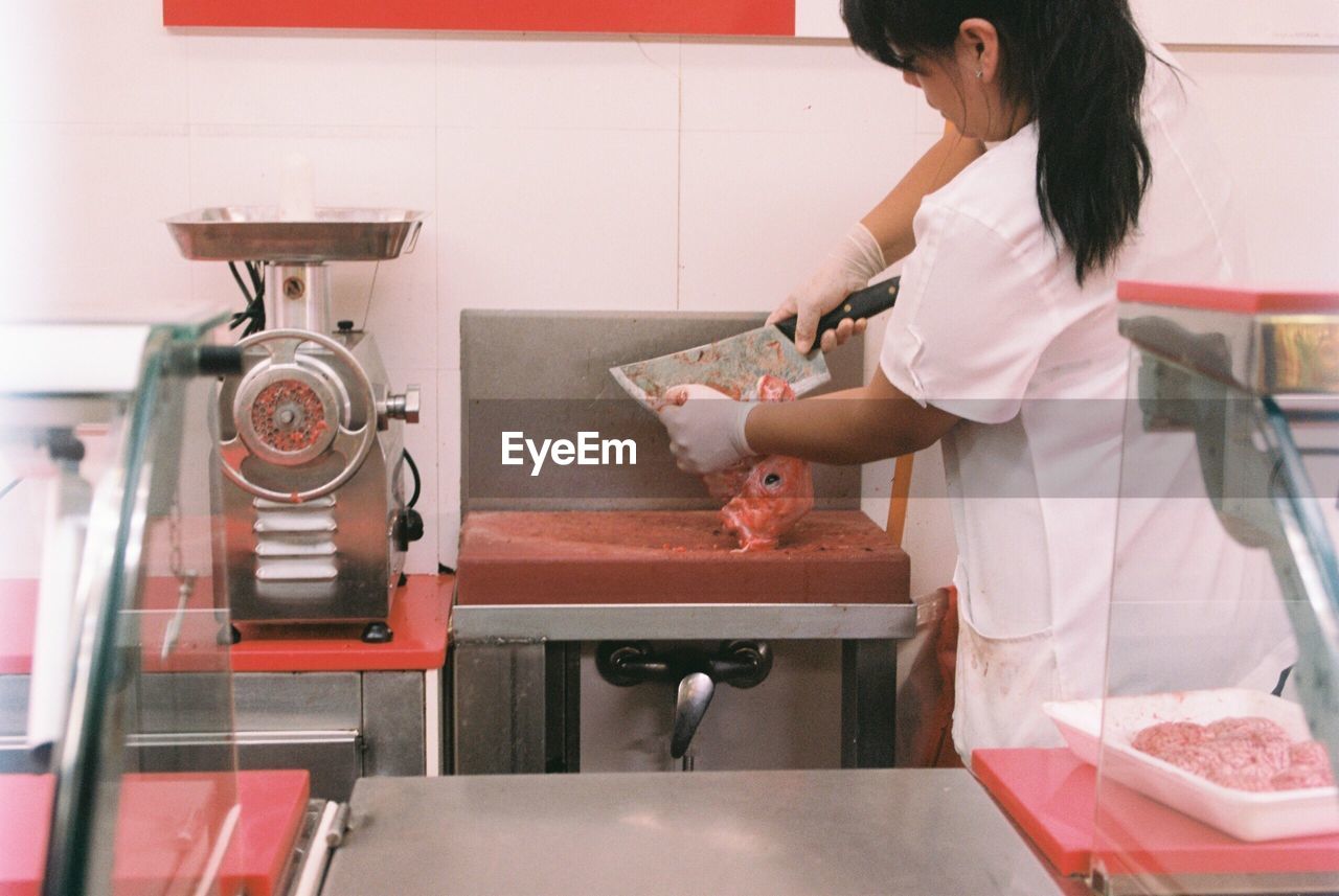 Rear view of butcher slicing meat in shop