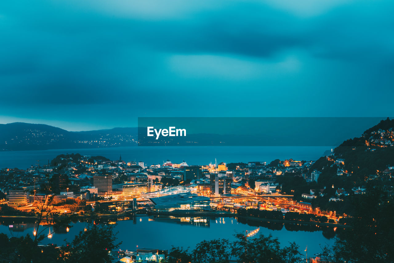 High angle view of illuminated city by sea against sky