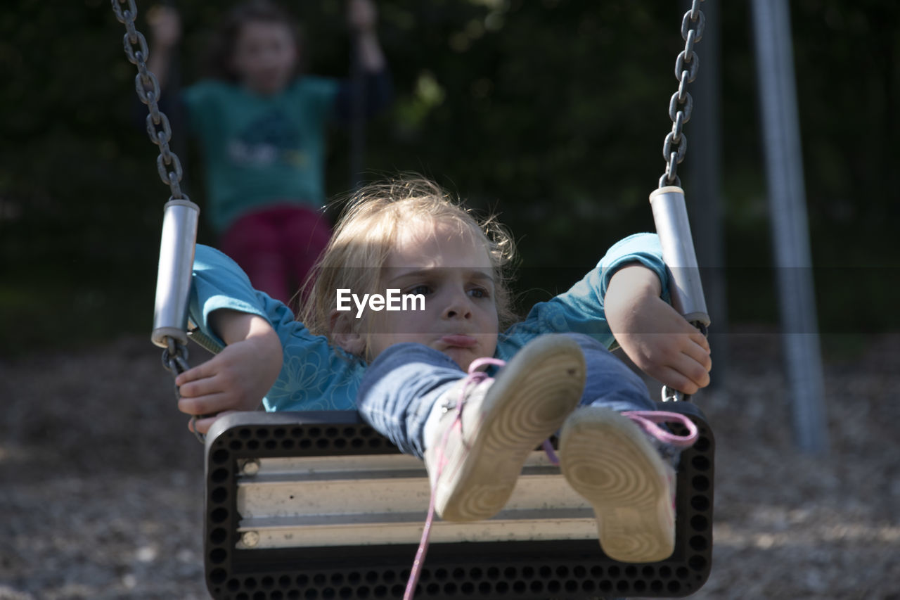 Rear view of people sitting on swing at playground