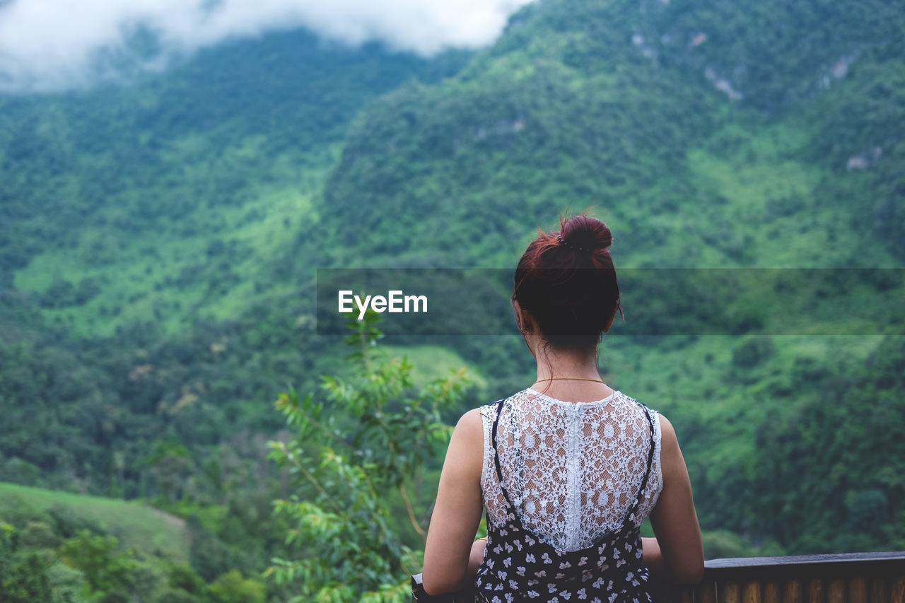 Rear view of woman standing in balcony against mountain