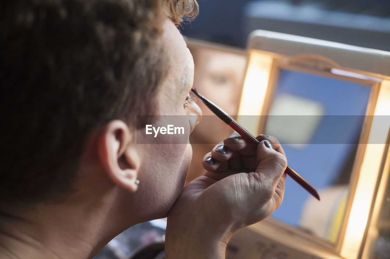 Young man applying drag makeup