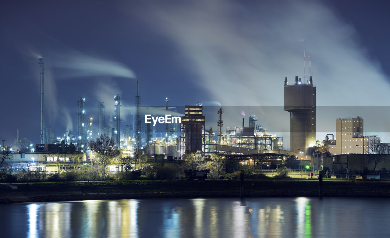 Illuminated petrochemical industry factory by a river at night