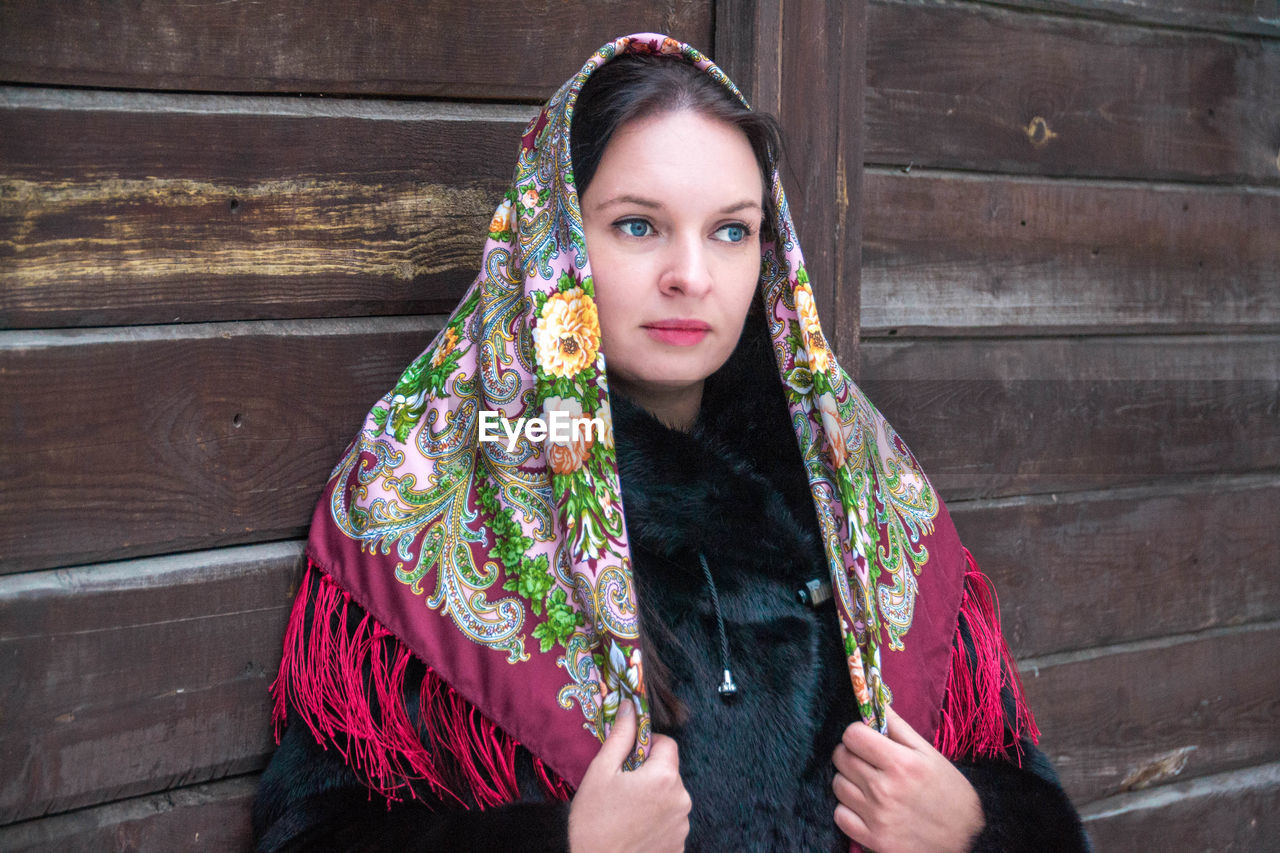 Smiling woman with blue eyes standing by wood