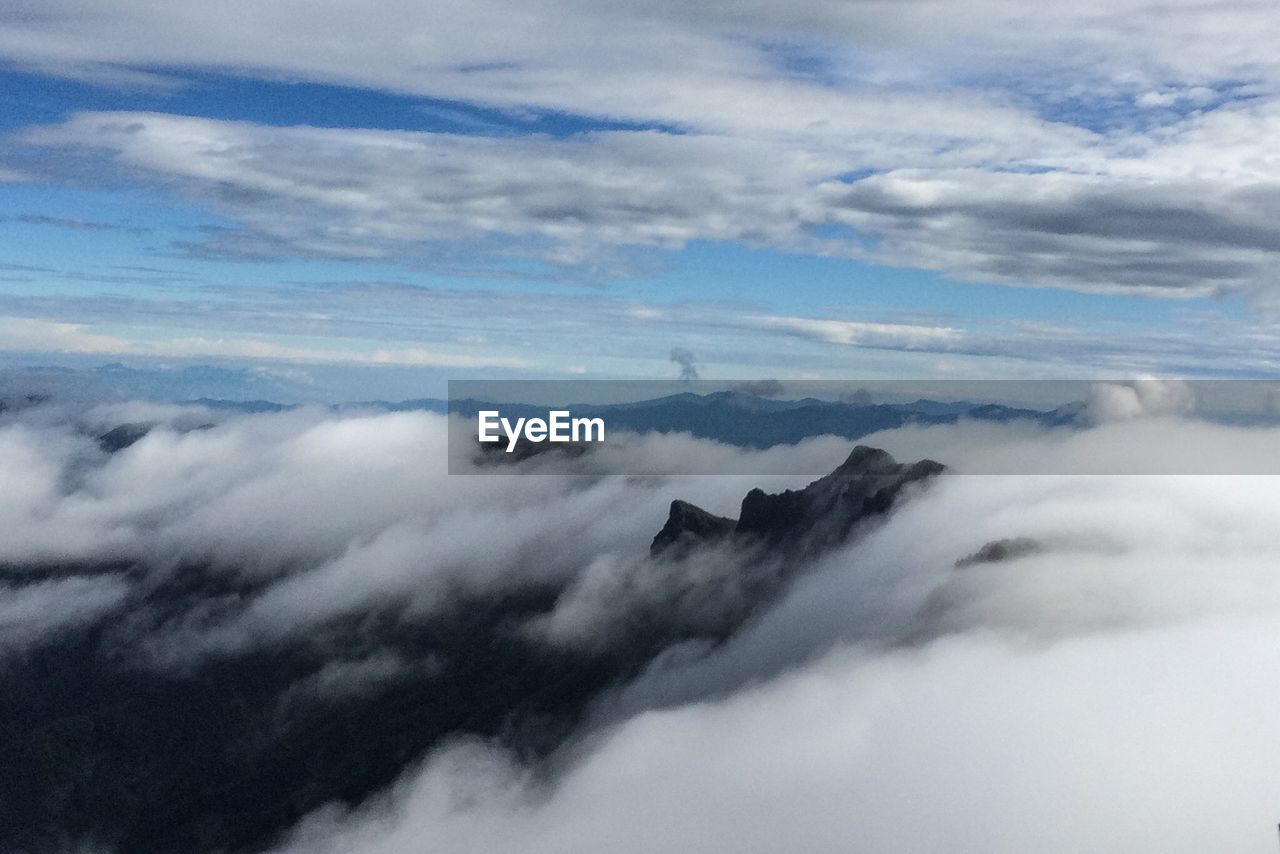 Fog covered mountains against cloudy sky
