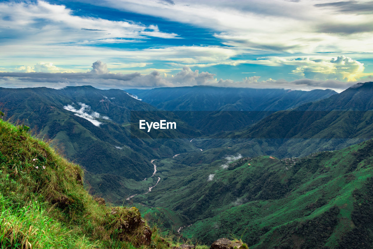 Mountain valley covered with green forests and bright blue sky at morning