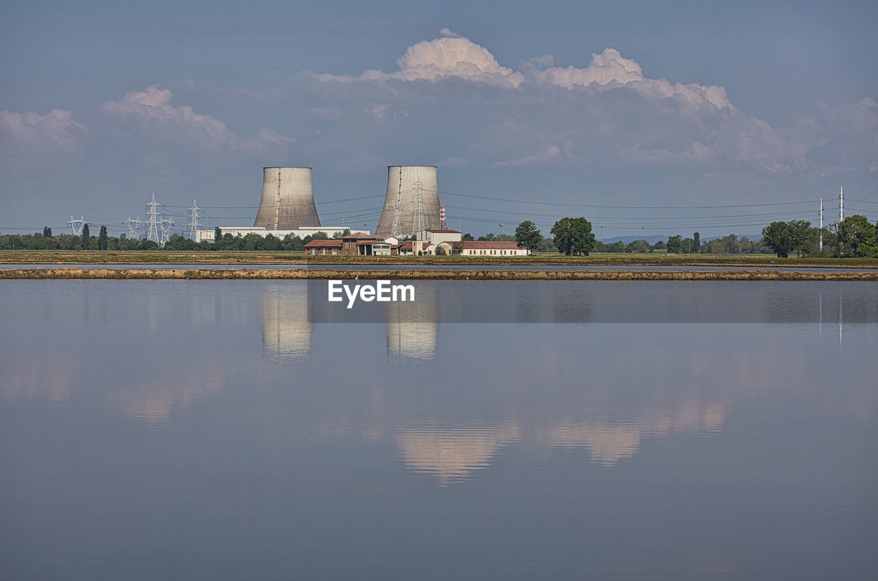 reflection, water, horizon, architecture, skyline, morning, sky, built structure, cloud, building exterior, dusk, nature, city, environment, lake, industry, landscape, building, cityscape, outdoors, no people, skyscraper, business finance and industry, travel destinations, reservoir, power station, sunlight, factory, tree