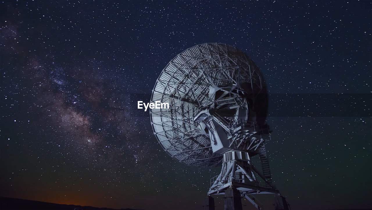Low angle view of radio telescope against star field at night