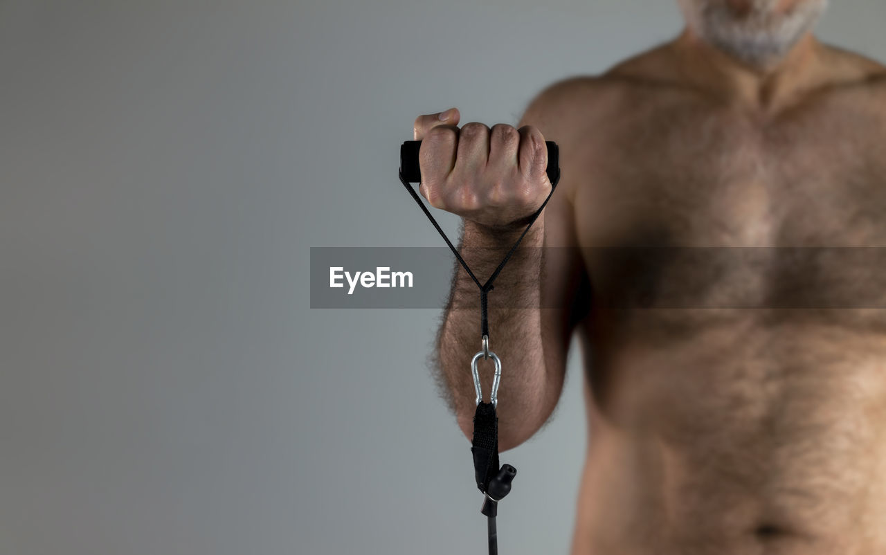 Closeup of hand training with elastic band with shirtless man in background