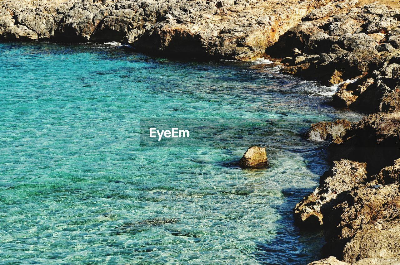 HIGH ANGLE VIEW OF ROCK FORMATIONS BY SEA