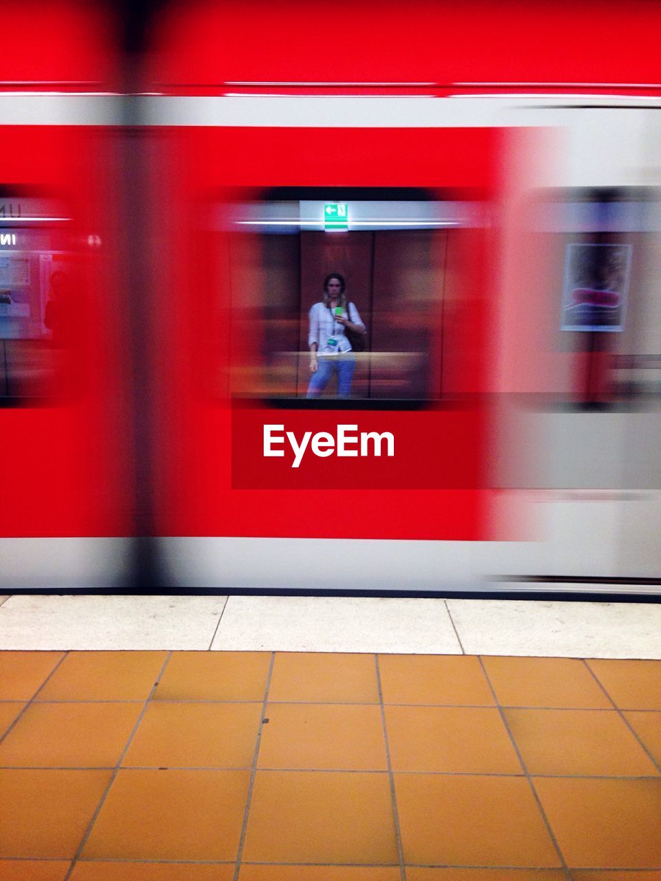 Reflection of person on red train window at subway station