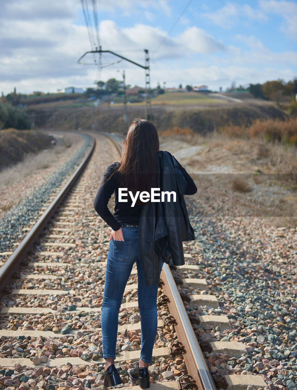 Rear view of woman walking on railroad track