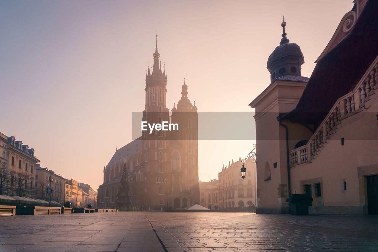 Famous empty paved main square with historic buildings with towers located in city of poland against cloudless sky in krakow