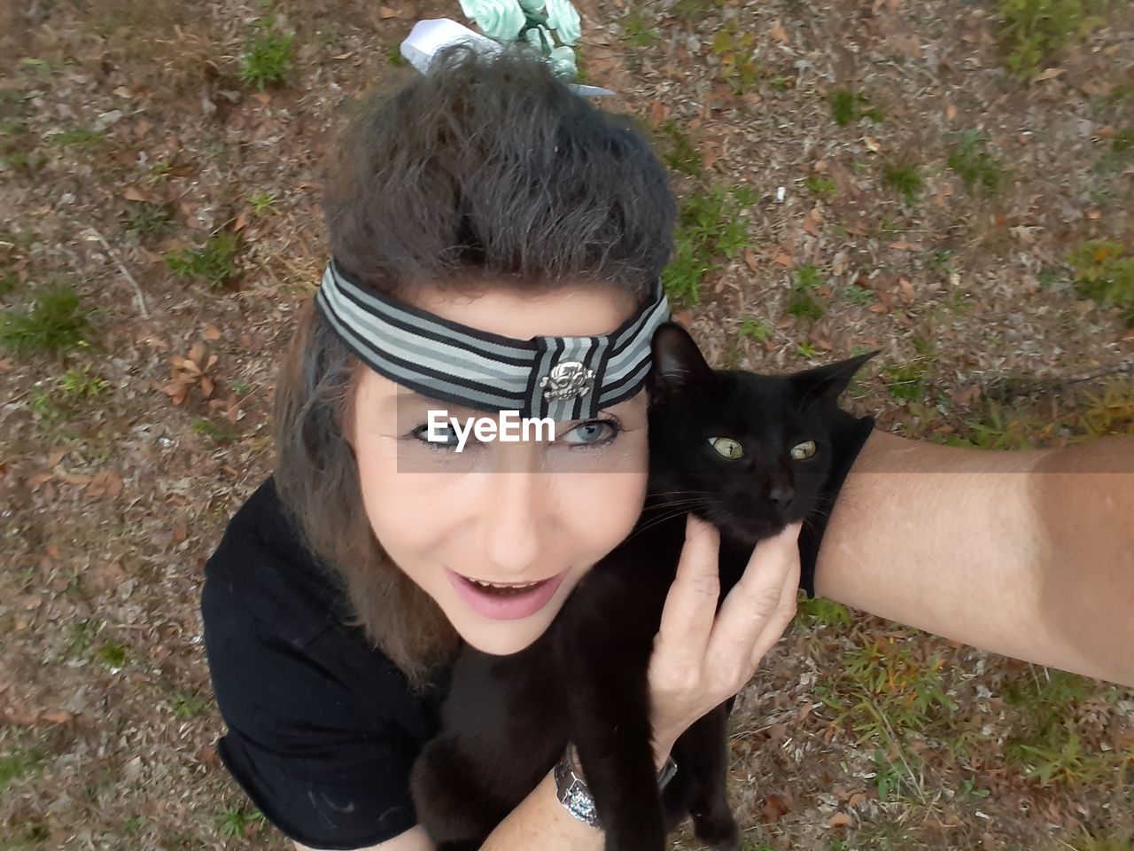 Woman wearing headband holding cat outdoors