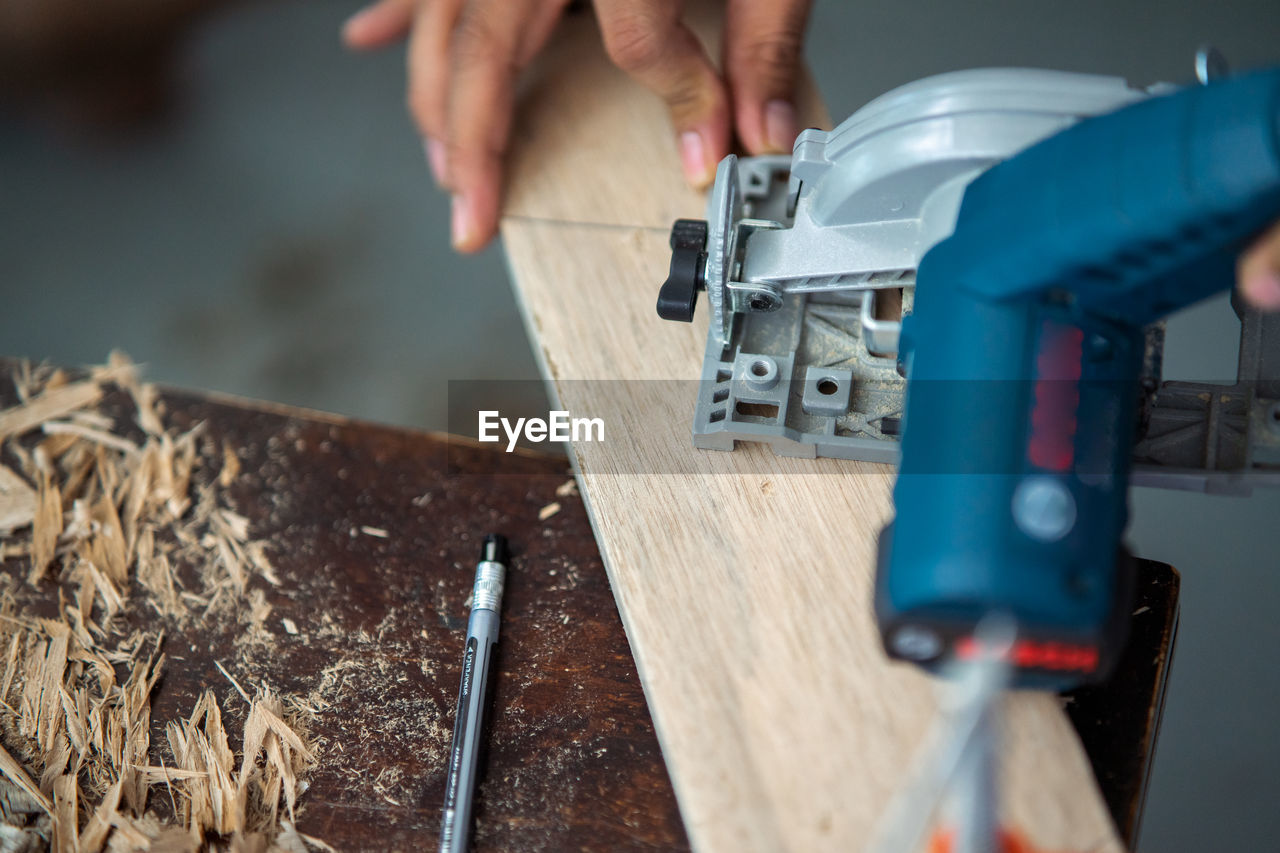Close-up of a carpenter using a circular saw to cut a plank of wood