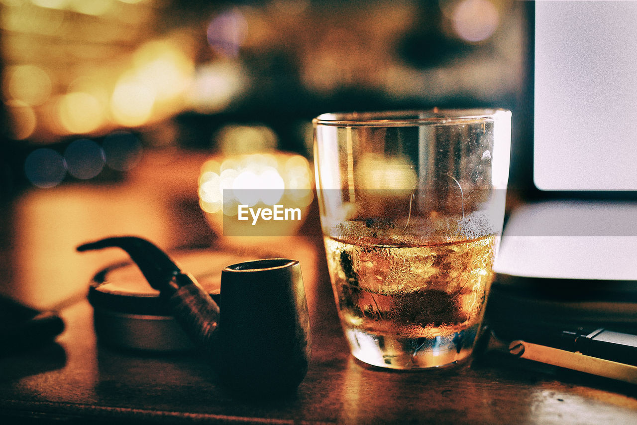 Close-up of alcohol in glass by smoking pipe on table