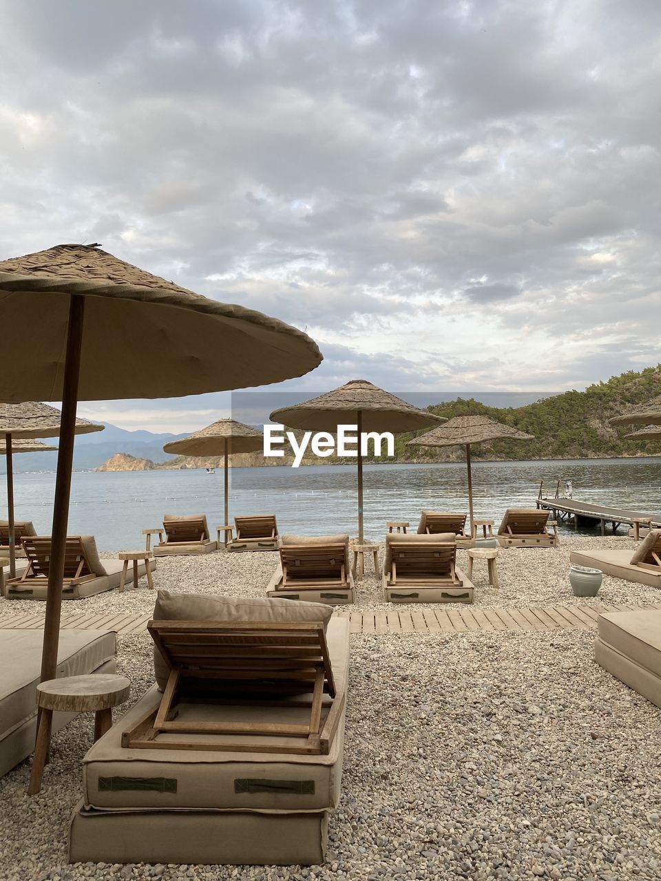 LOUNGE CHAIRS AND TABLES ON BEACH AGAINST SKY