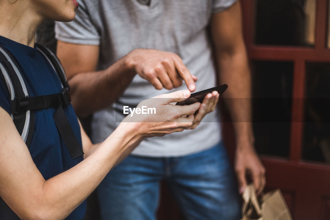 MIDSECTION OF MAN HOLDING SMART PHONE