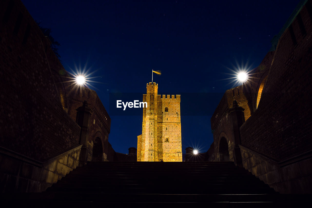 LOW ANGLE VIEW OF ILLUMINATED BELL TOWER AT NIGHT