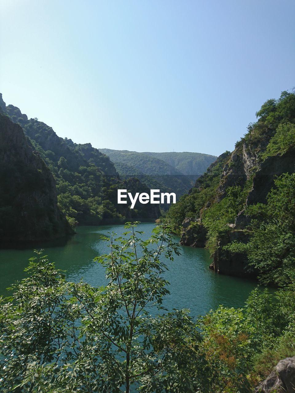 Scenic view of river by mountains against clear sky