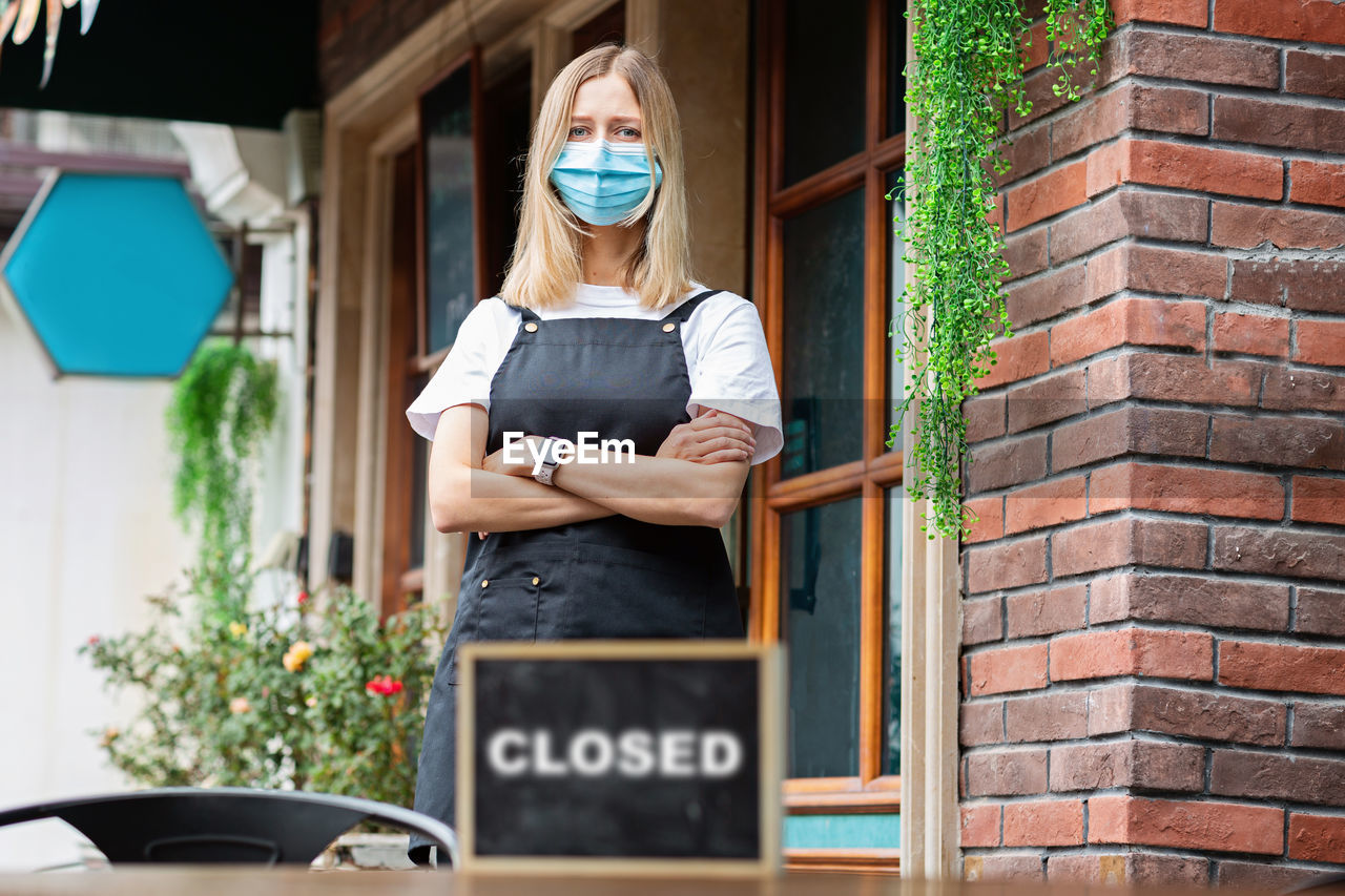 Caucasian waitress woman wearing medical mask, cafe  closed. coronavirus covid-19 pandemic