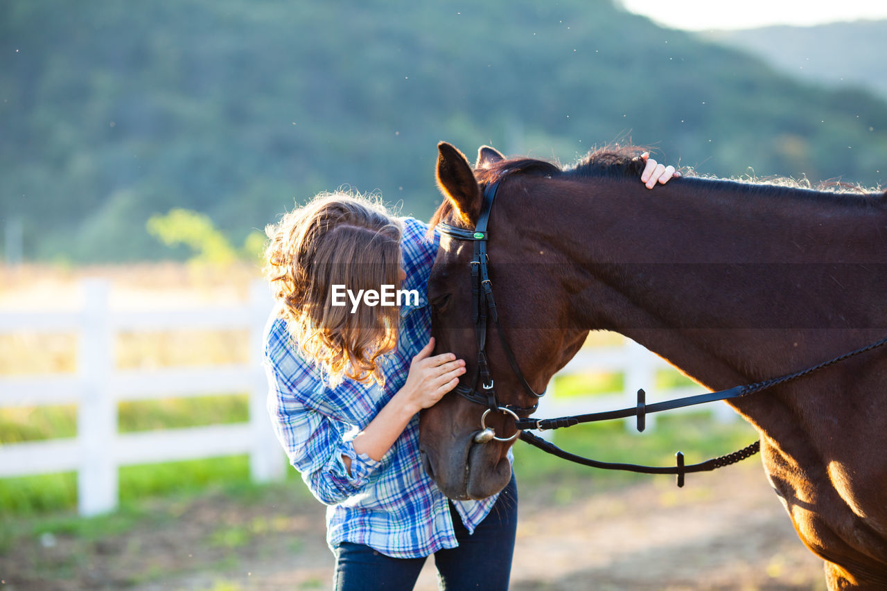 Young woman with horse standing on field