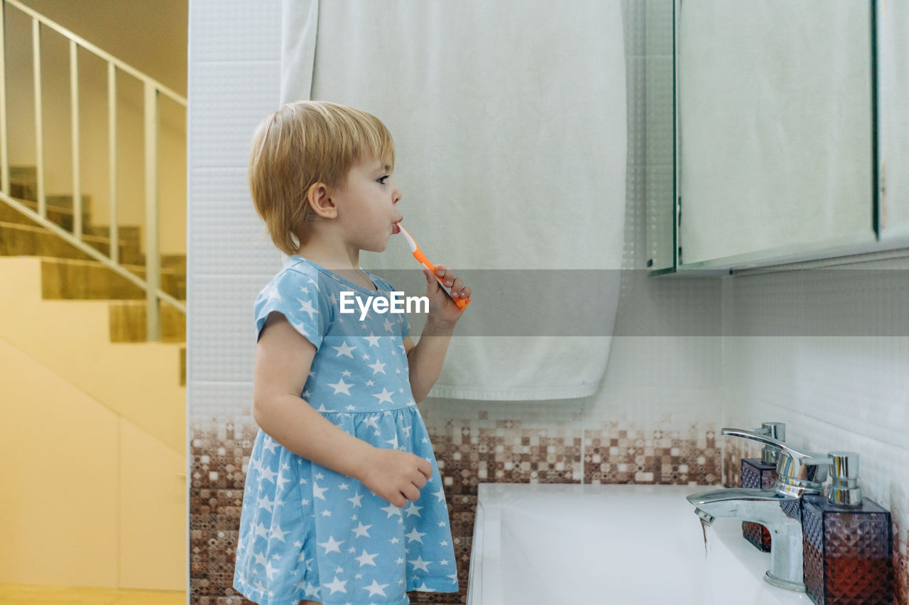 Little toddler girl brushes her teeth in the bathroom.