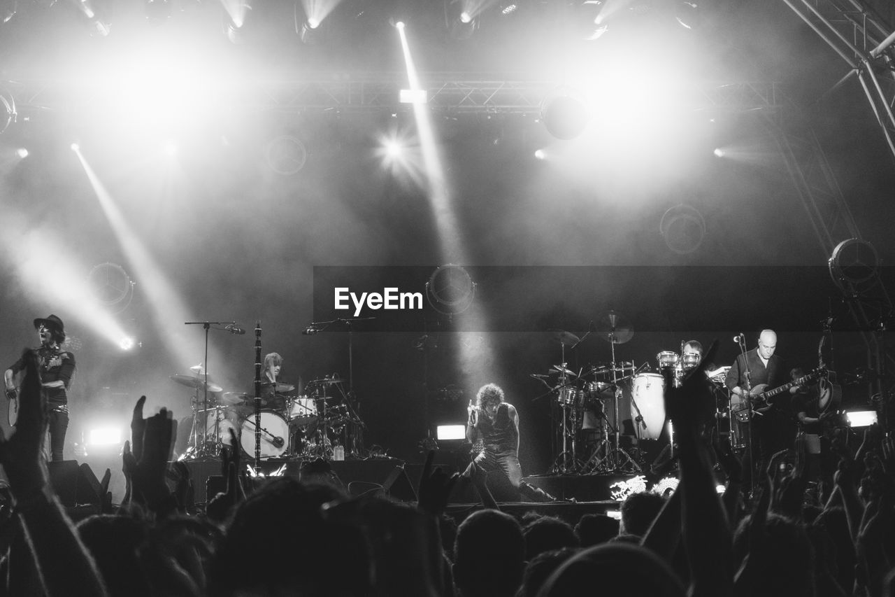 Spectators looking at musicians performing on stage during concert