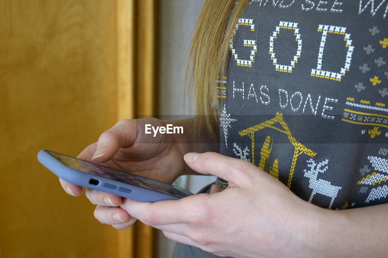 Girl holds samrtphone in her hands. she browses information on mobile phone screen. close-up.