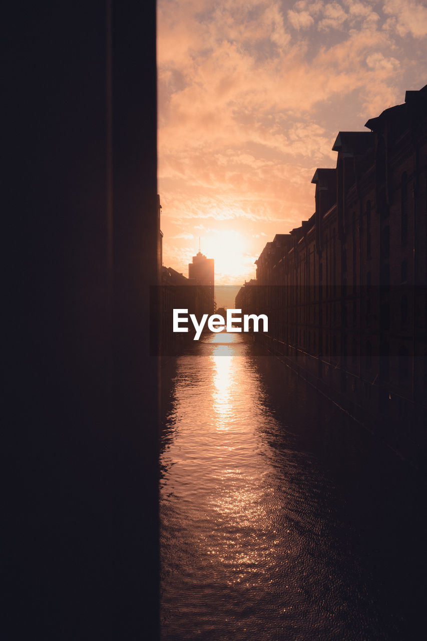 Canal amidst buildings against sky during sunset