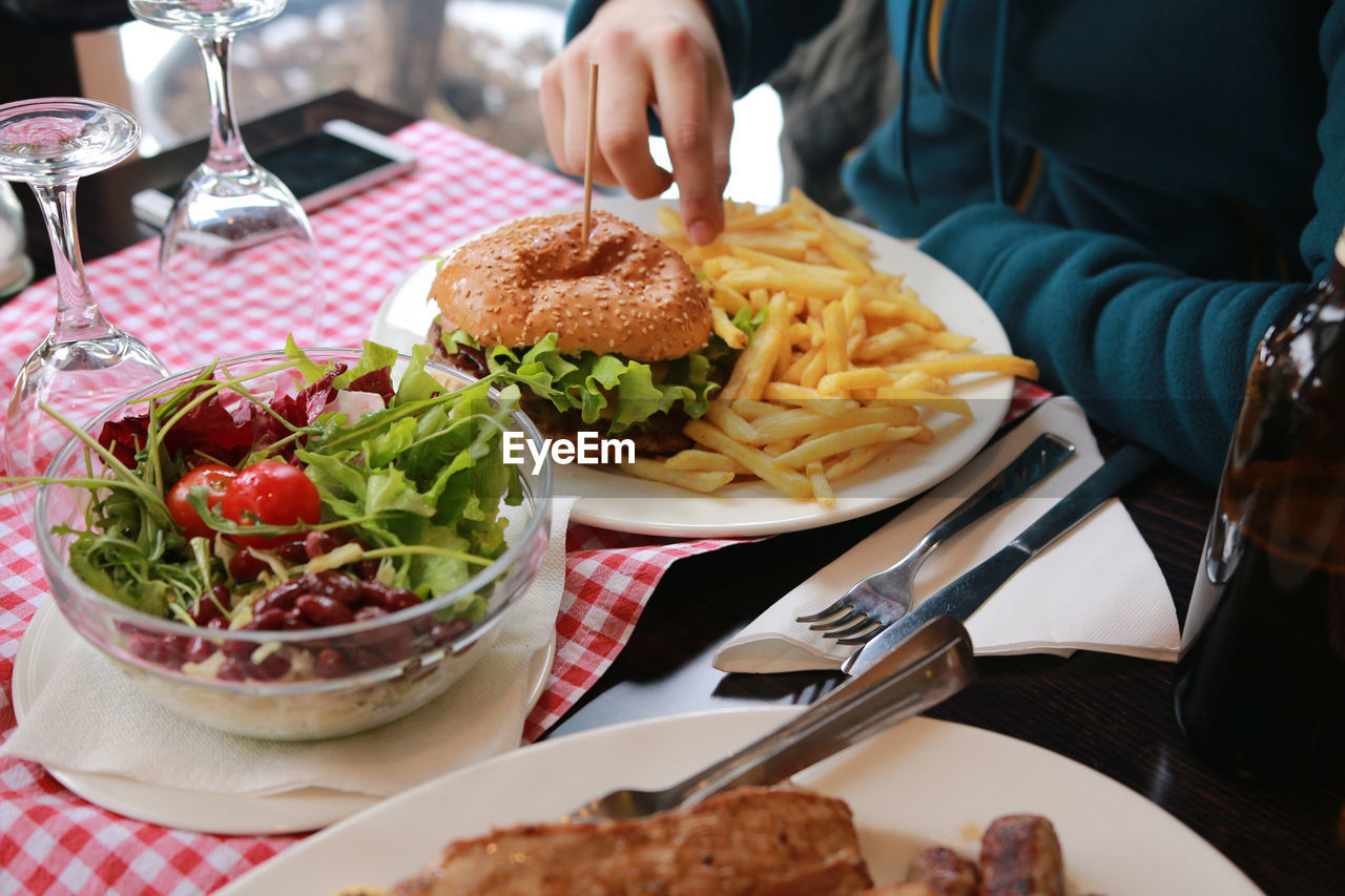 Midsection of woman having burger at table