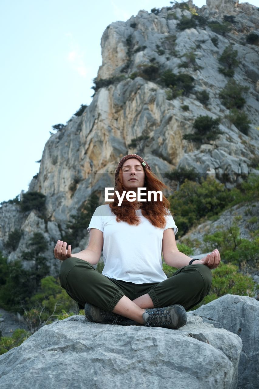 Woman sitting in lotus position on rock