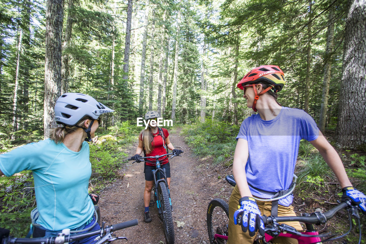 Three female friends mountain bike on a trail at mt. hood, oregon.