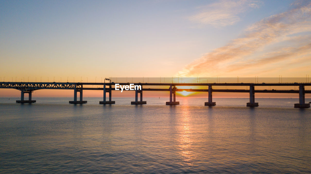 Silhouette of bridge over sea against sky during sunset