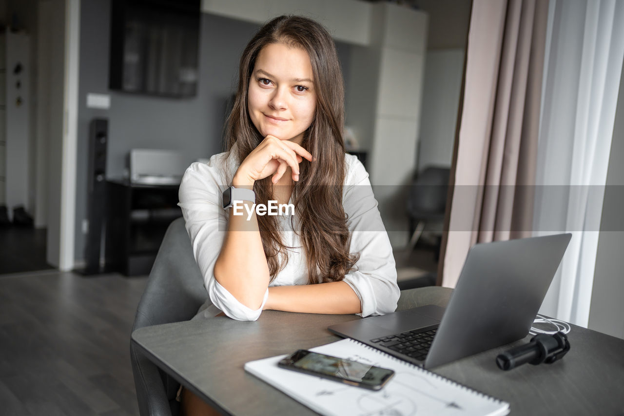 portrait of young woman using laptop at home