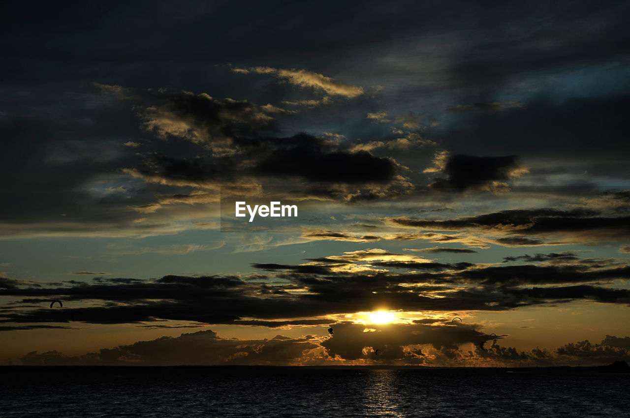 Scenic view of sea against dramatic sky during sunset