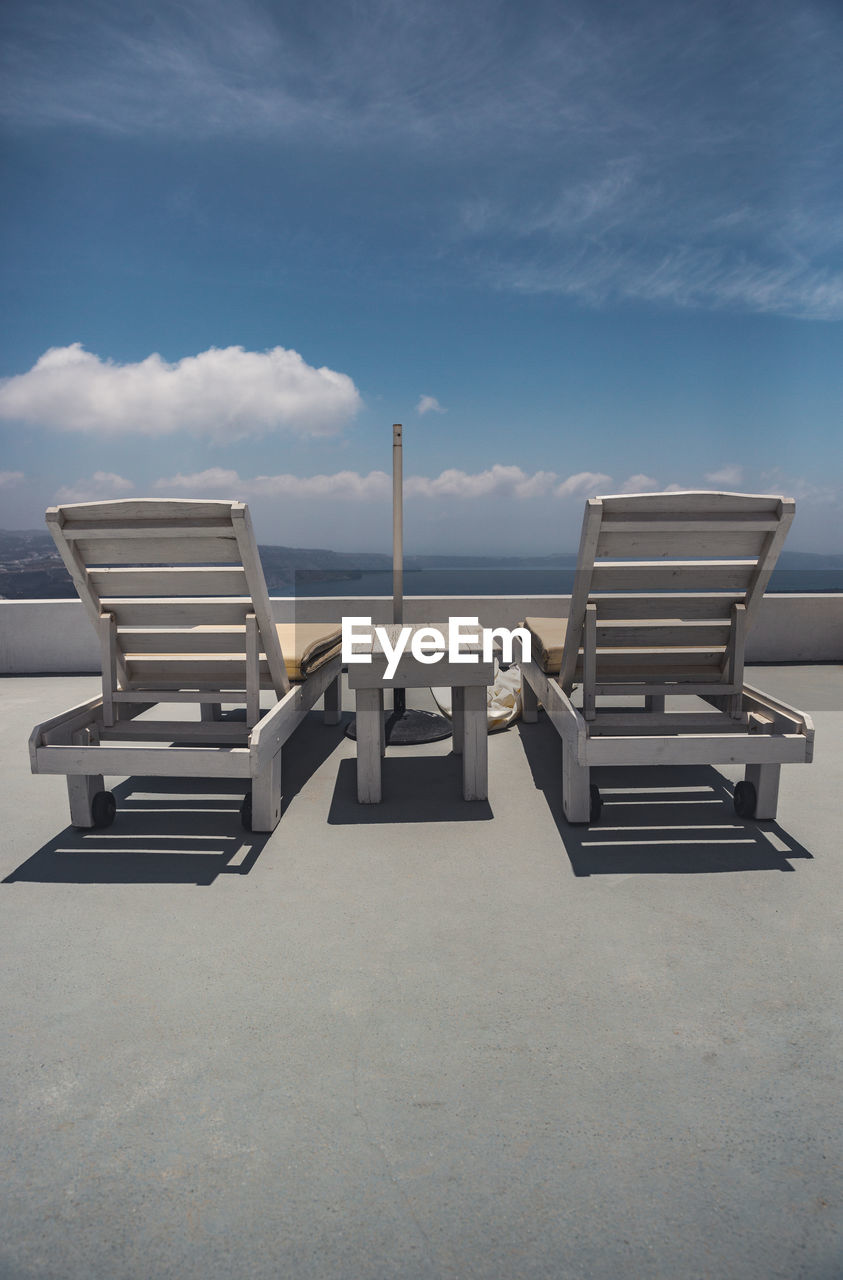 Empty chairs on beach against sky santorini 