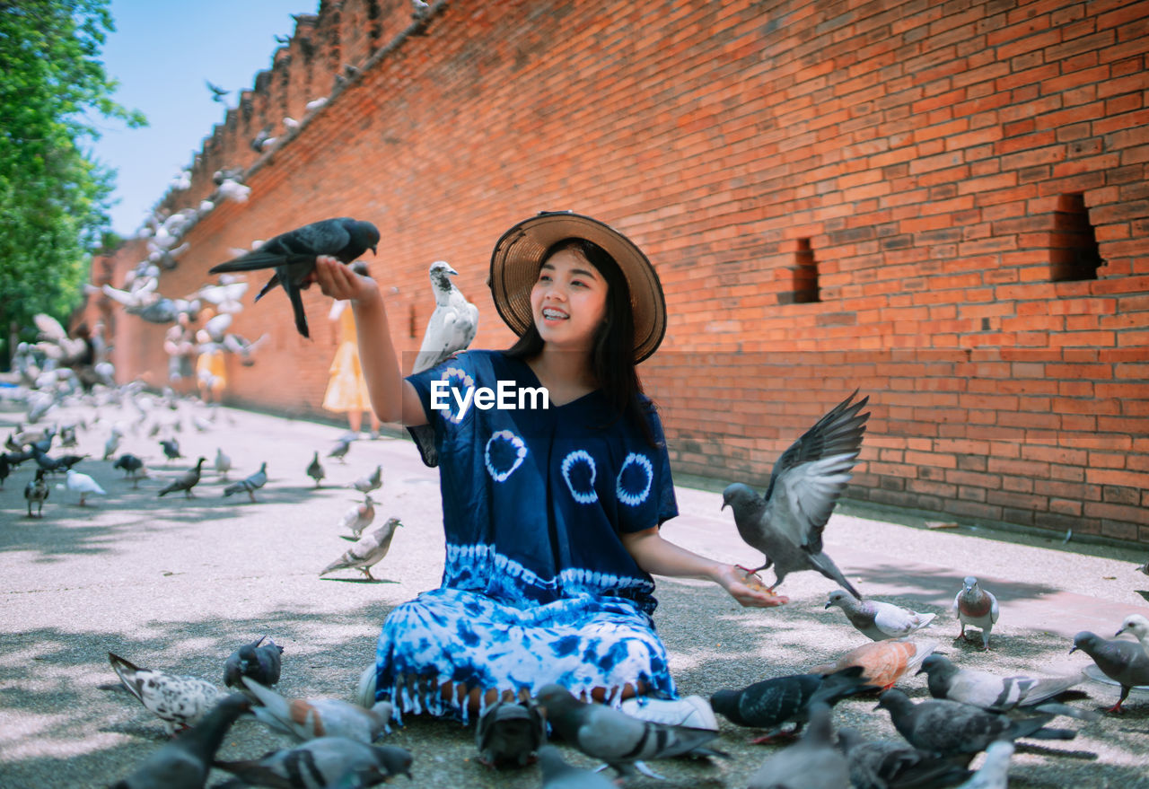 Young woman playing with pigeons