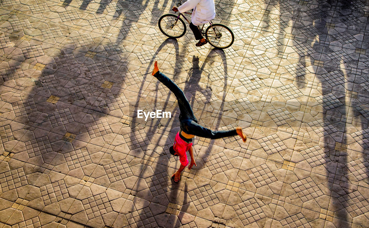 HIGH ANGLE VIEW OF MAN RIDING BICYCLE ON FOOTPATH
