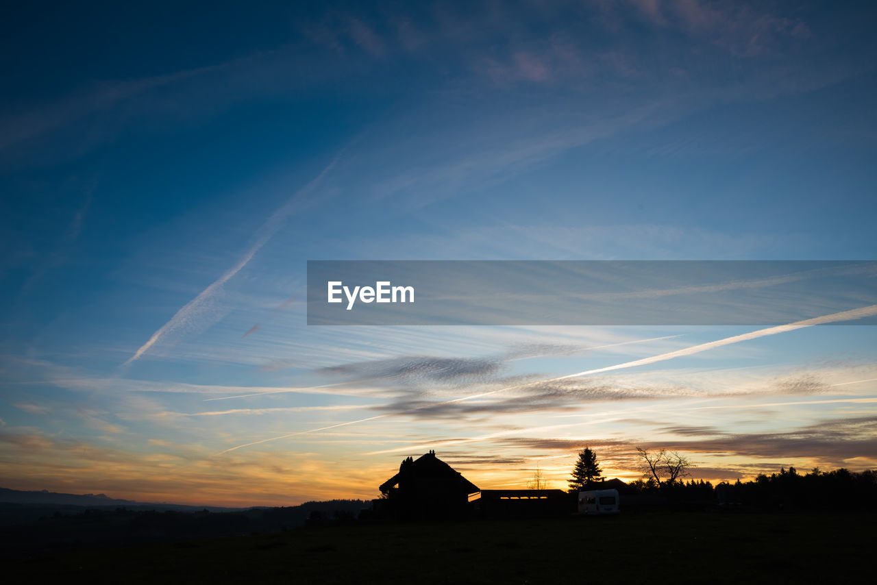 Silhouette houses against sky during sunset