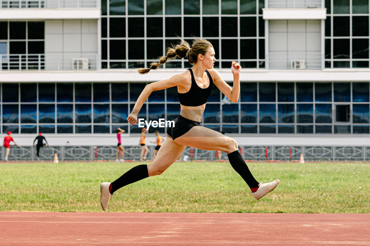 side view of young woman exercising on field