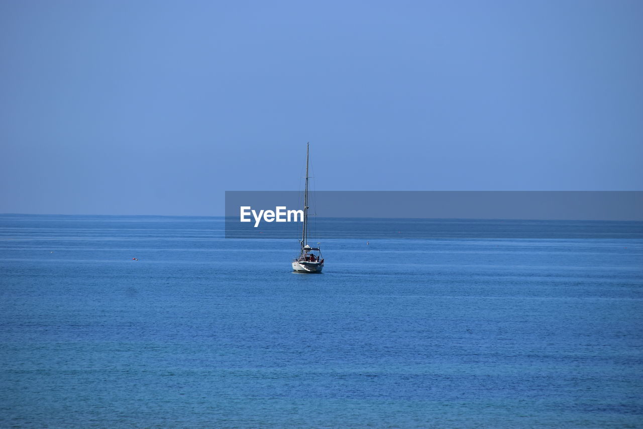 Sailboat sailing on sea against blue sky