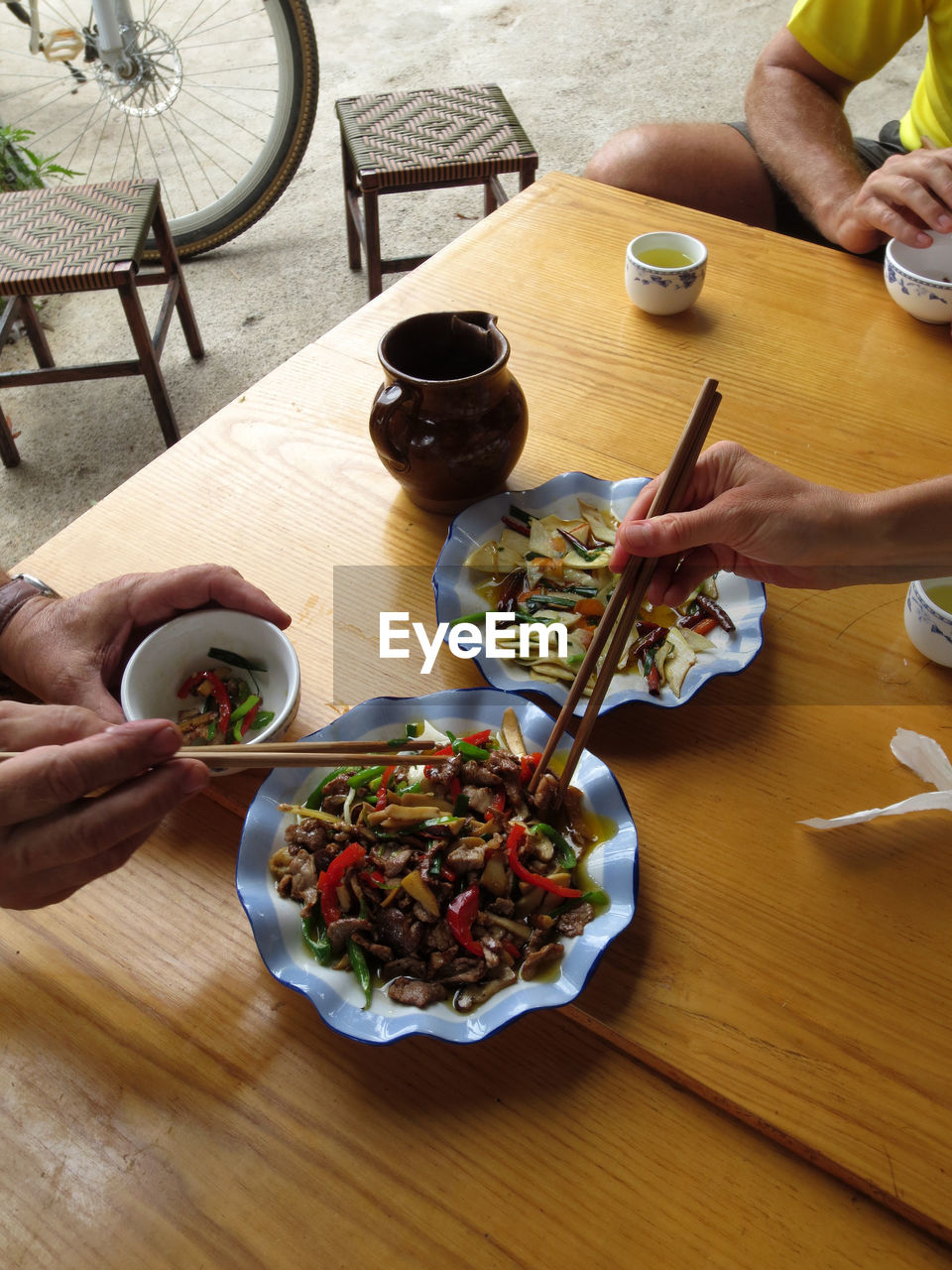 HIGH ANGLE VIEW OF PEOPLE EATING FOOD IN BOWL