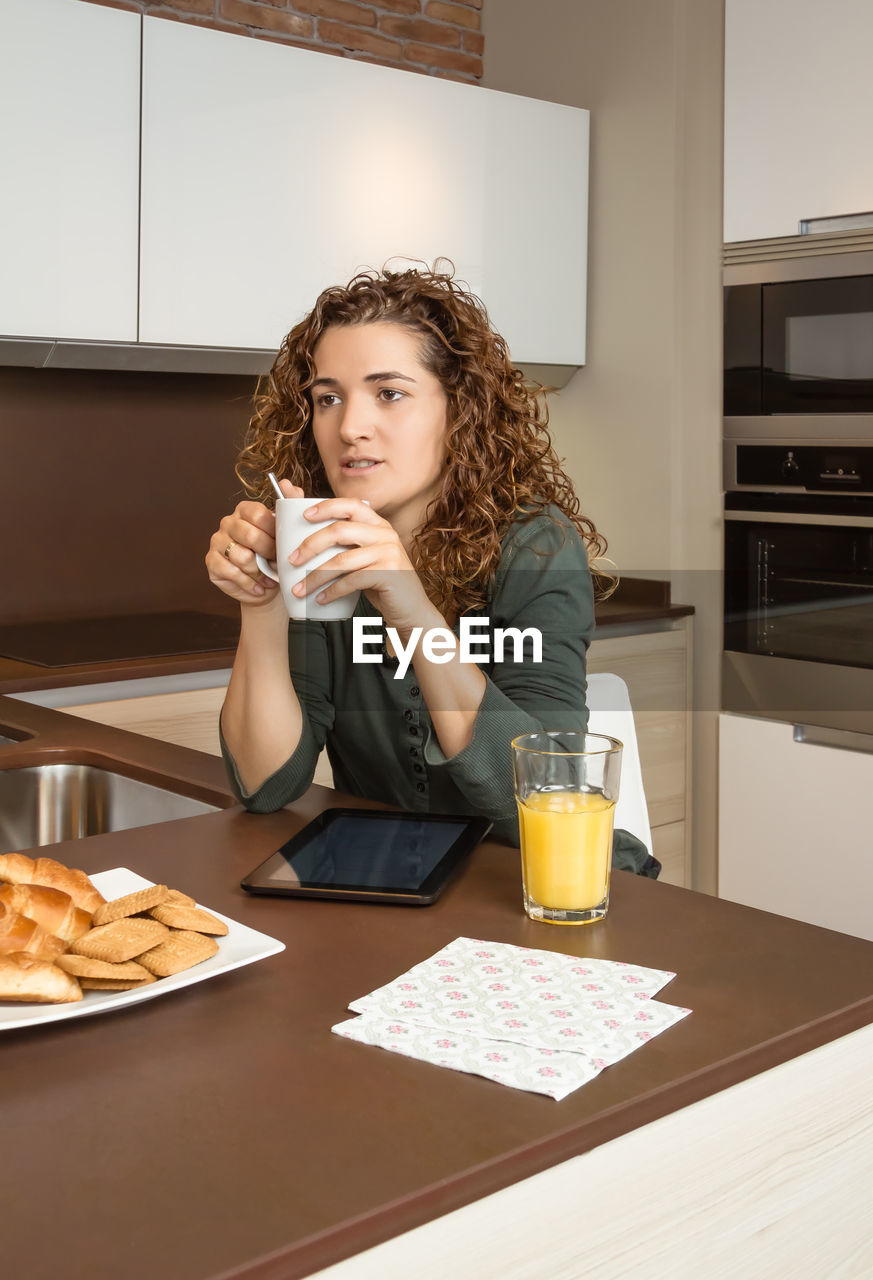 Woman holding coffee cup on table at home