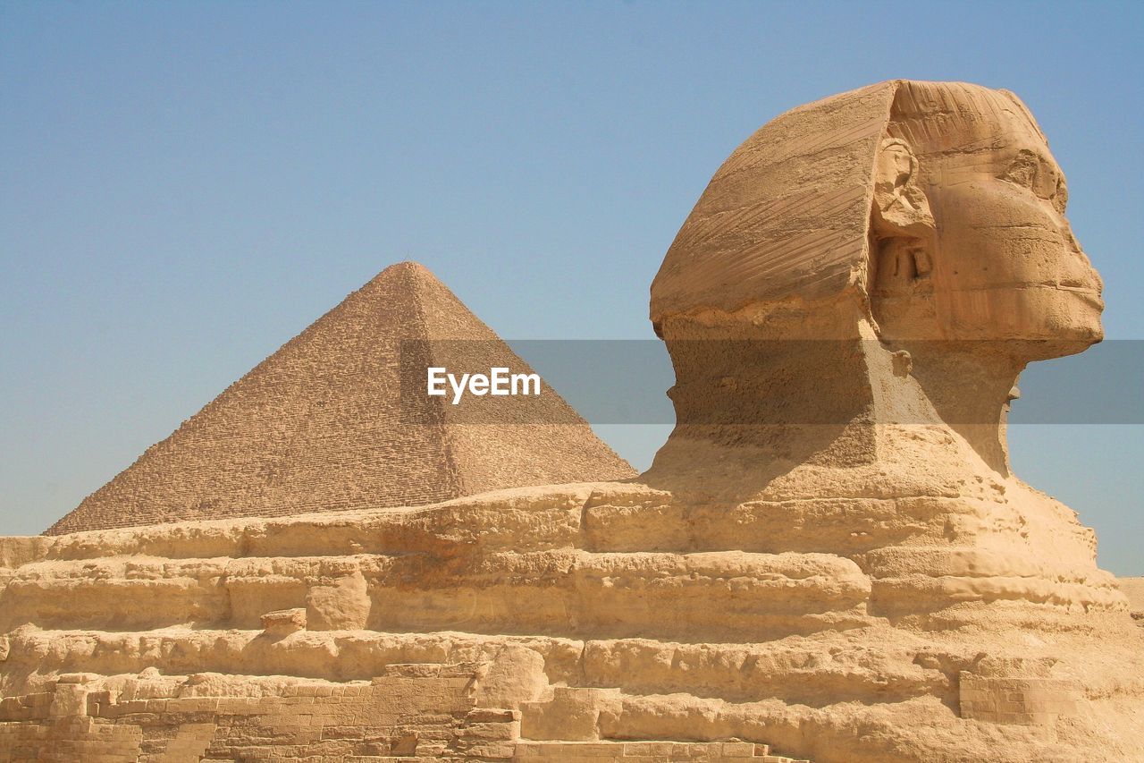 Great sphinx and pyramid against clear sky