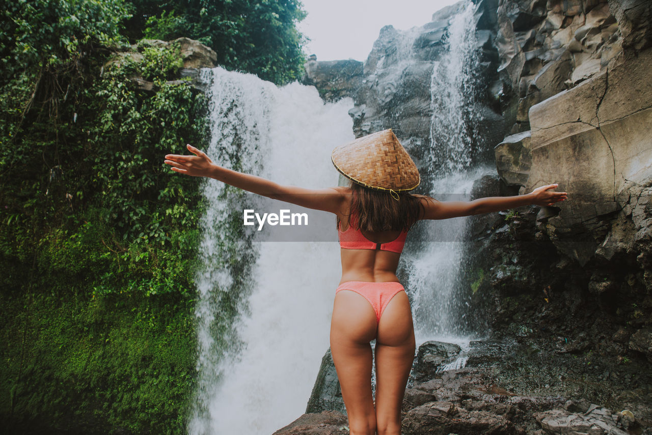 Young woman standing against waterfall