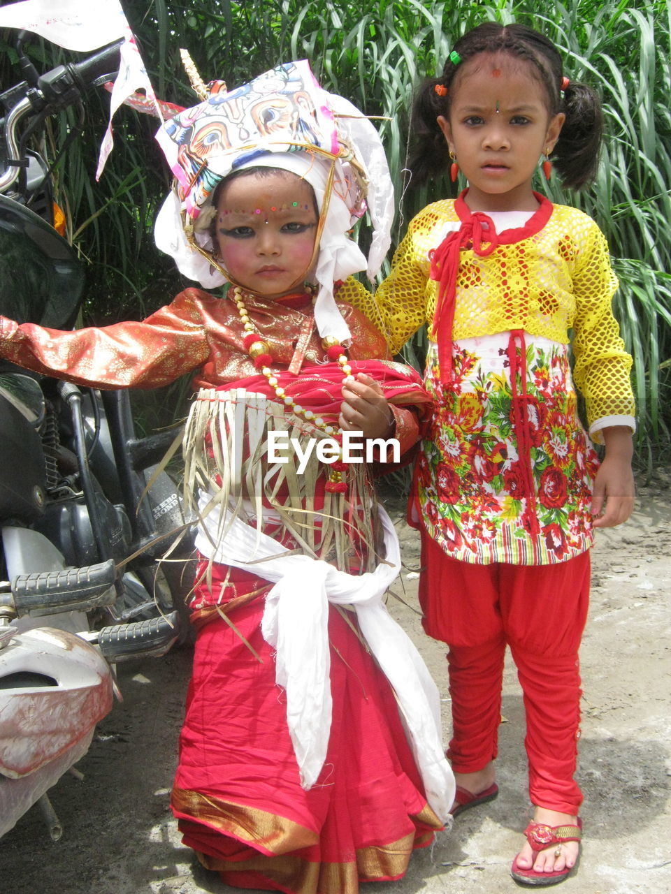 PORTRAIT OF HAPPY GIRL STANDING AGAINST TRADITIONAL CLOTHING