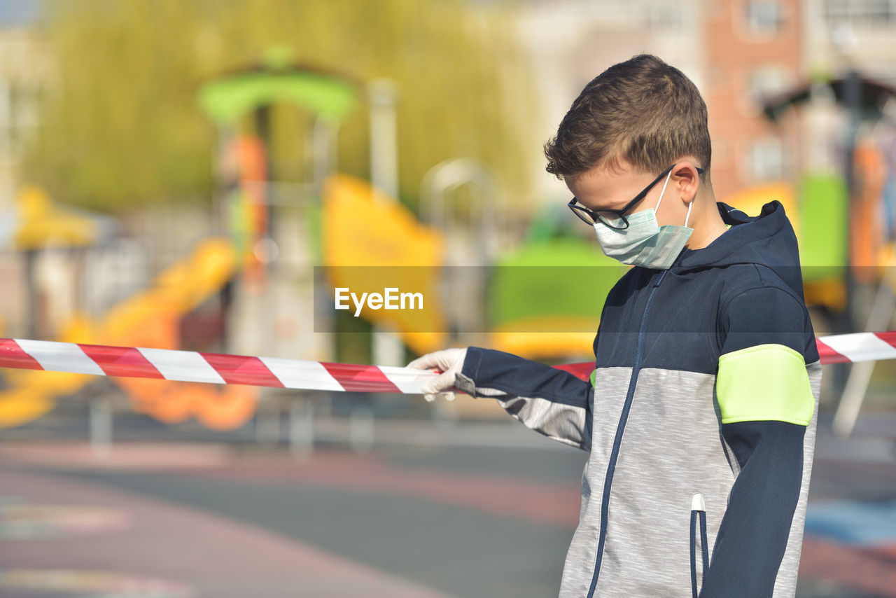 Close-up of boy wearing mask standing outdoors