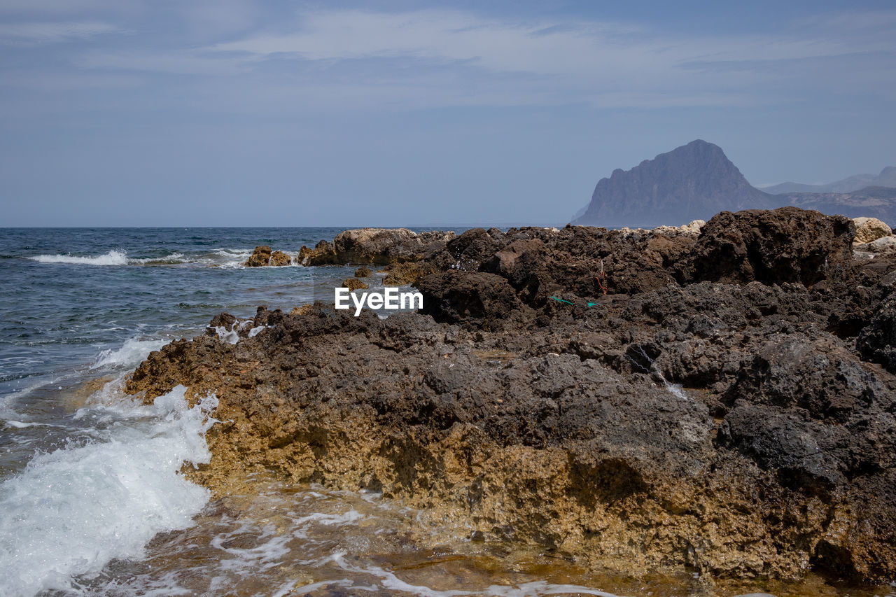 Rock formations on shore against sky