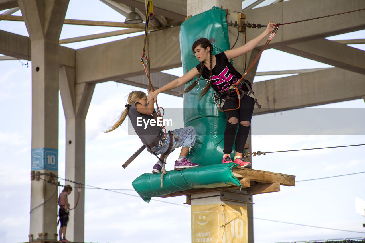 Low angle view of teenage girl walking on rope