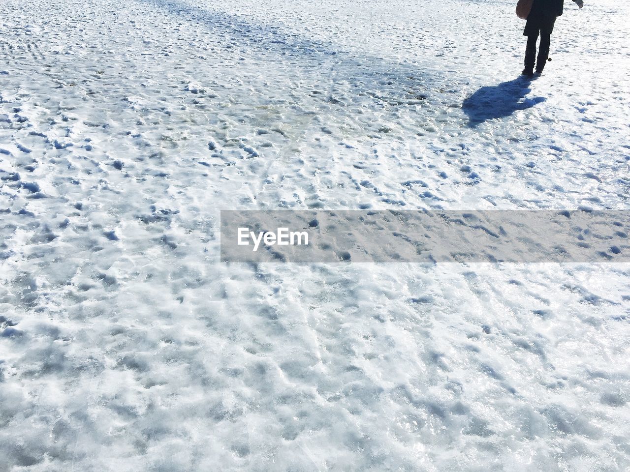 Low section of person walking on snow covered field